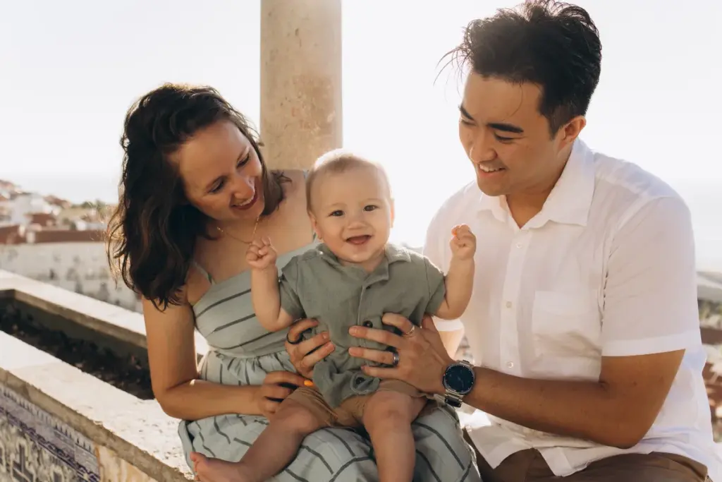 Parents and their smiling baby on a tiled bench at an Alfama viewpoint
