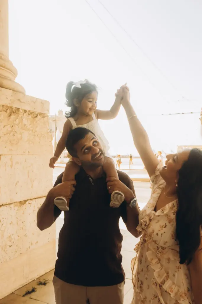 Toddler on her father's shoulders reaching for her mother at Praça do Comércio