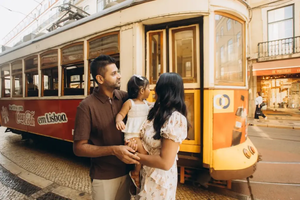 Family with a toddler beside a vintage tram in Baixa