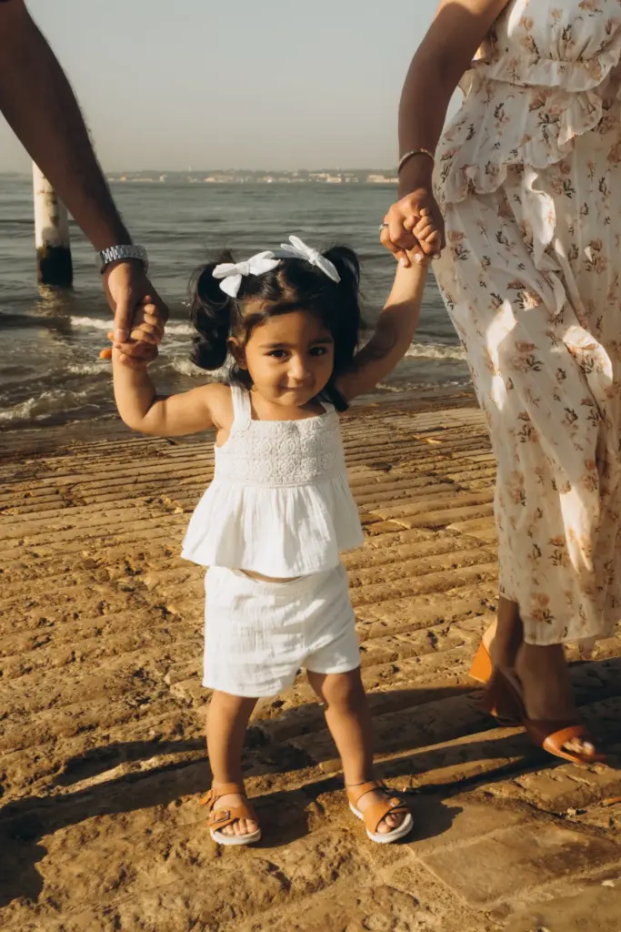 Toddler walking hand in hand with her parents at Cais das Colunas