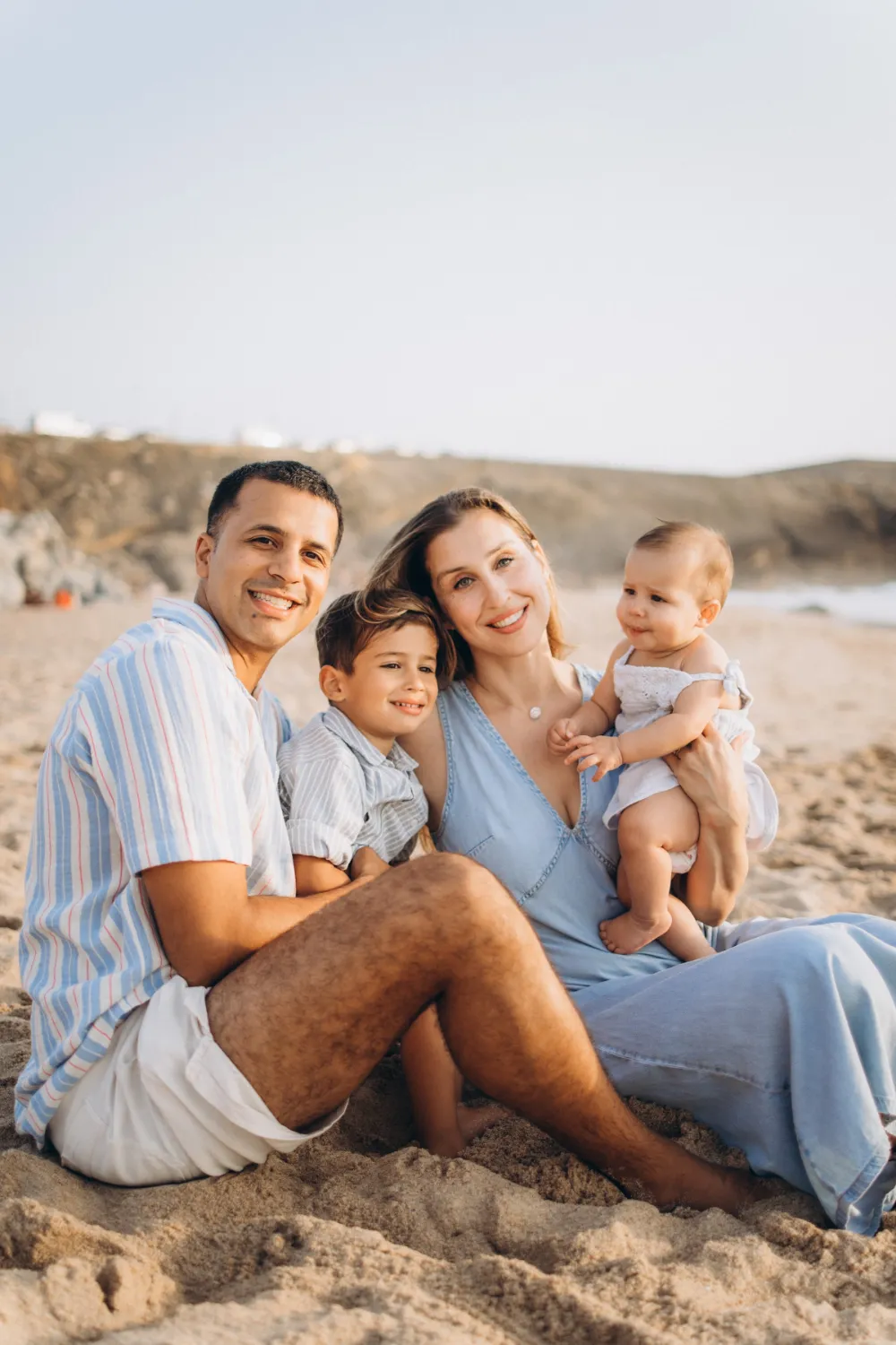 Family sitting on the sand on a beach near Cascais