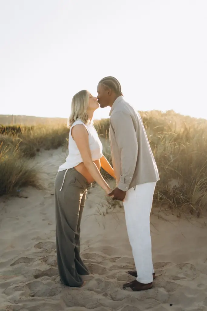 Expecting couple kissing in the dunes