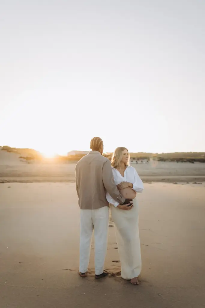 Expecting couple walking towards the dunes