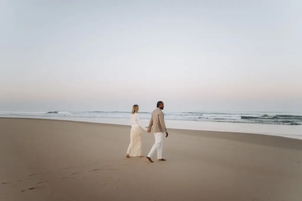 Expecting couple walking along the shore of an Atlantic beach near Lisbon