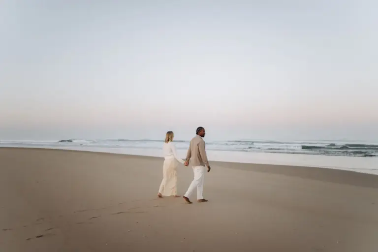 Expecting couple walking along the shore of an Atlantic beach near Lisbon