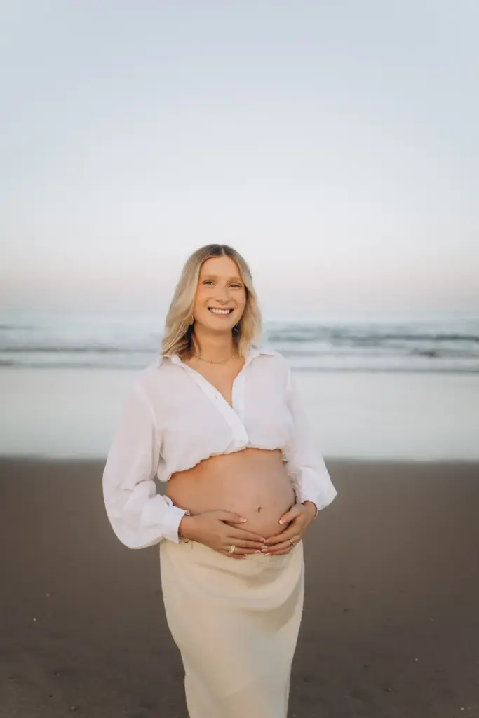 Pregnant woman smiling on the beach near Lisbon
