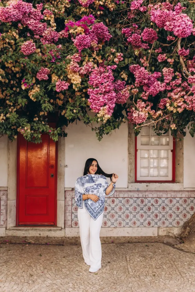 Woman standing under bougainvillea by a red door