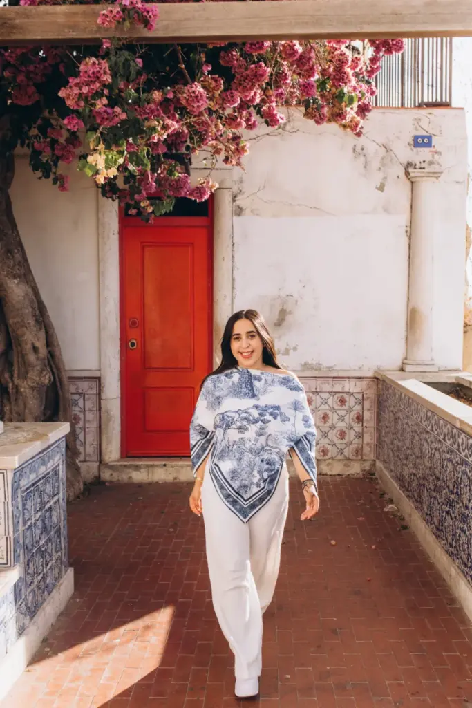 Woman walking by a red door under bougainvillea
