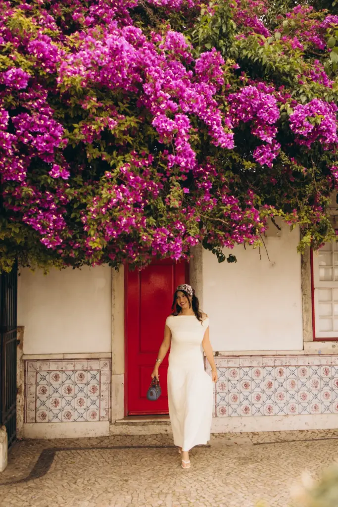 Woman by a red door under bougainvillea in Alfama