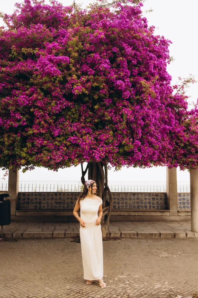 Woman under a bougainvillea tree at an Alfama viewpoint