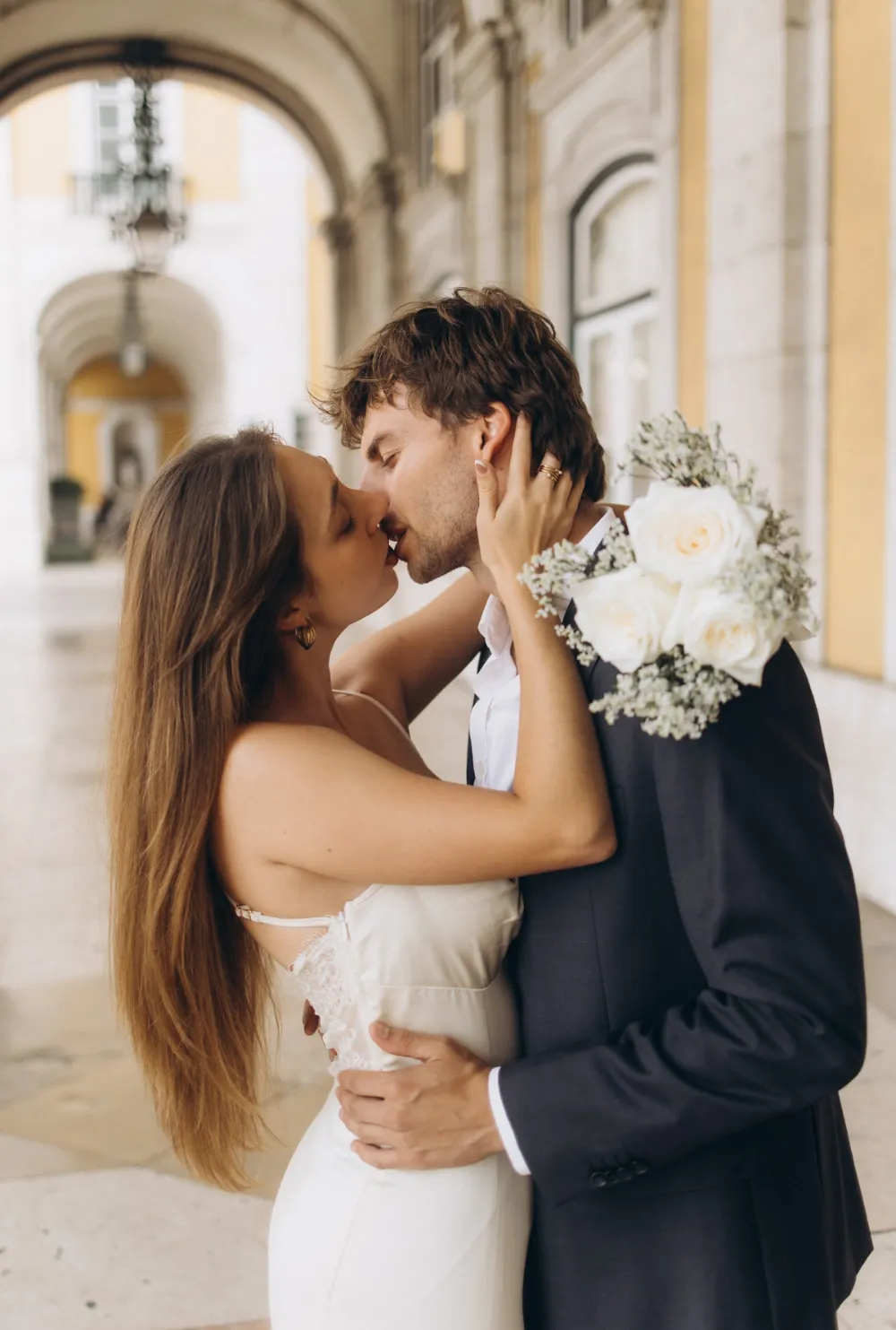 Bride and groom kissing under the arcades of Praça do Comércio