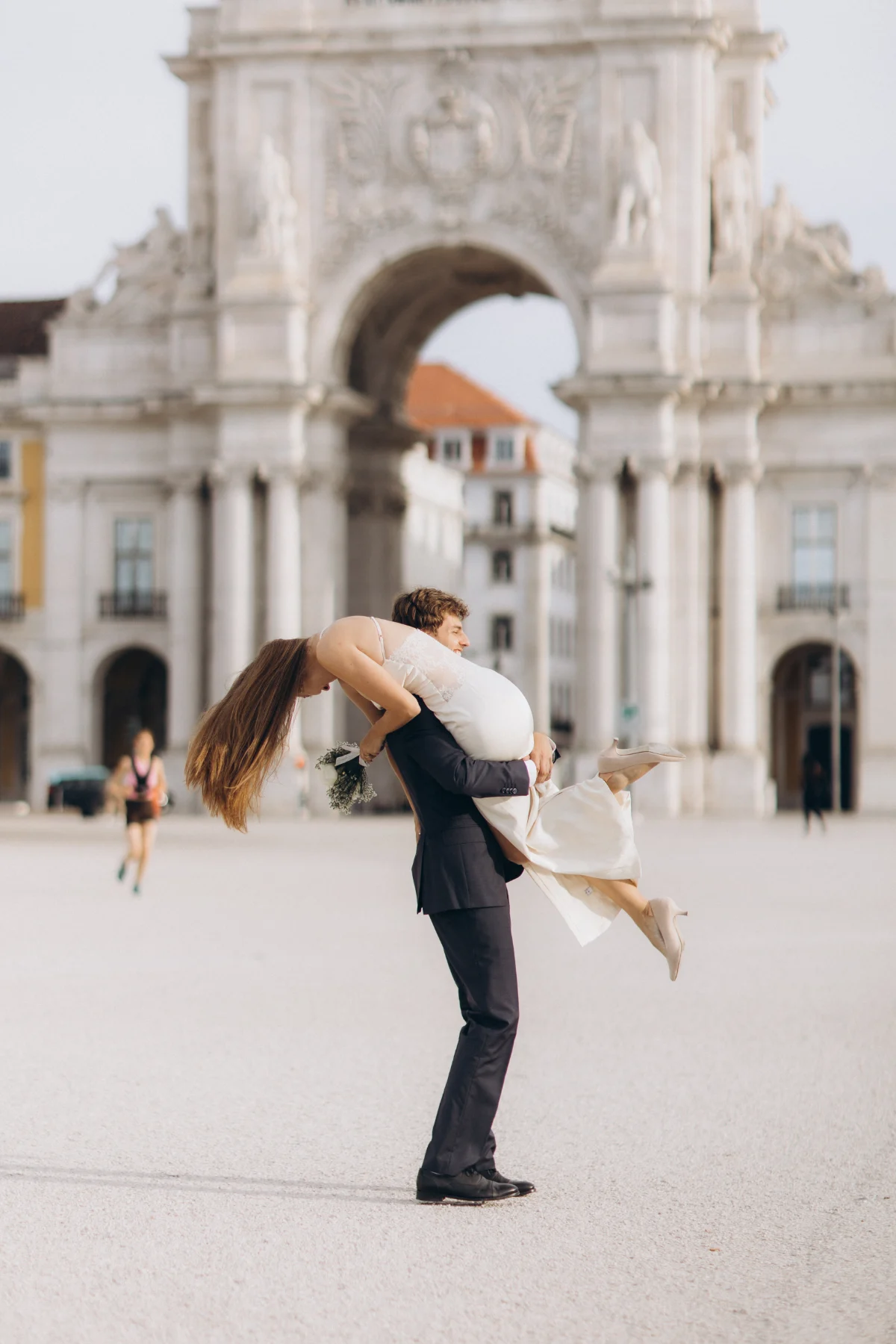 Groom lifting the bride in front of the Rua Augusta Arch, Praça do Comércio