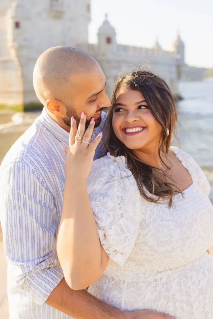 Couple laughing in front of Belém Tower during a maternity photoshoot