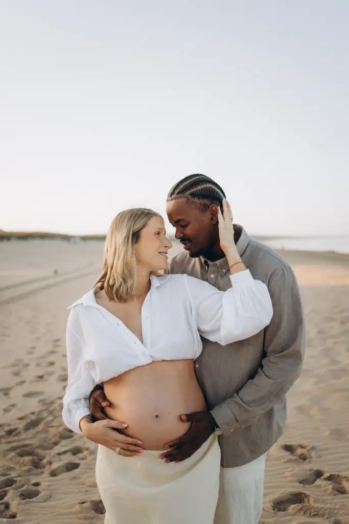 Couple on the beach near Lisbon, his hands on her bump